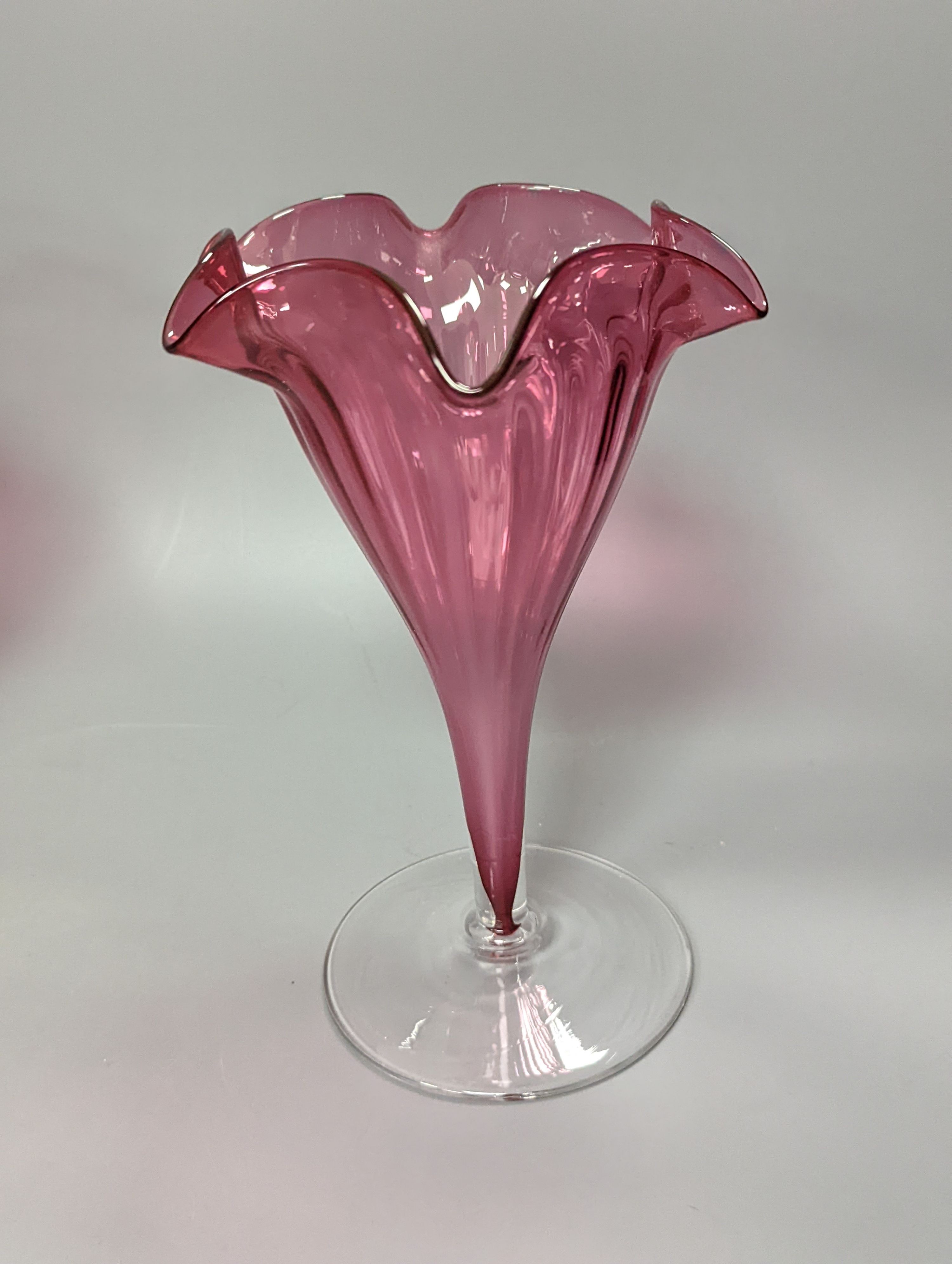 A pair of late Victorian cranberry glass frill vases, height 23cm, and a similar tapering jug